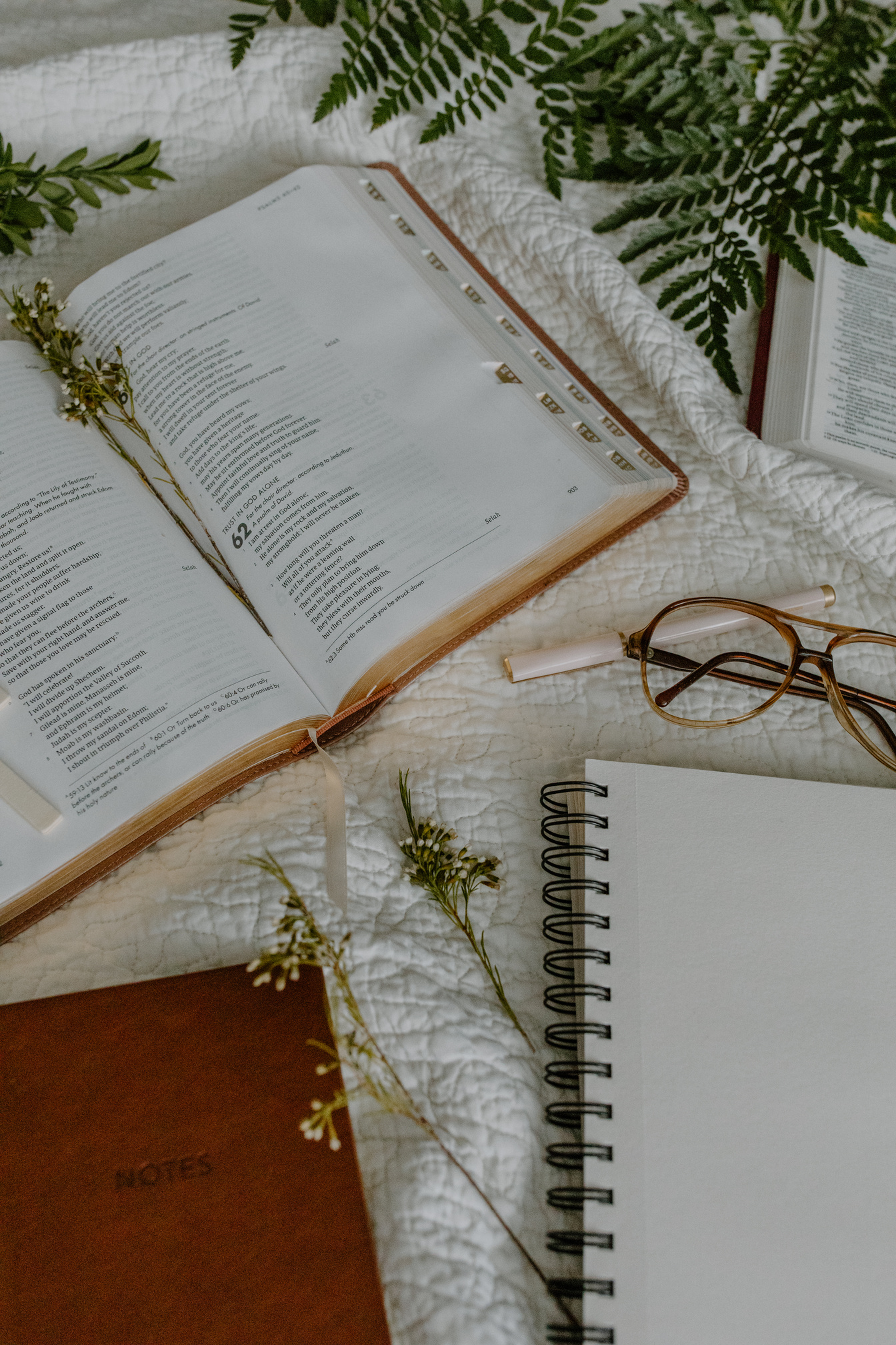 Eyeglasses Near Spiral Notebook and Bible